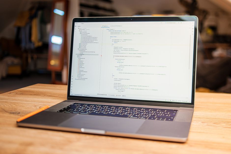 Otvoreni laptop s prikazanim programskim kodom na drvenom stolu u radnom prostoru